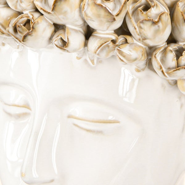 Nahaufnahme eines Buddha-Kopfs aus glasierter Keramik mit floralen Verzierungen.