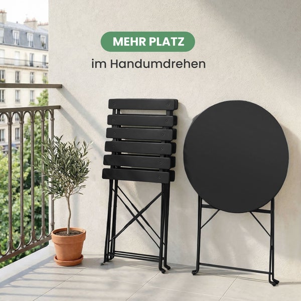 Bistro-Set für den Garten mit rundem Klapptisch und zwei Klappstühlen auf Kunstrasen, eine Frau sitzt lesend am Tisch.