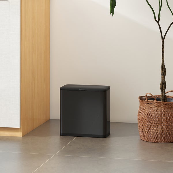 Abfalleimer mit Deckel neben Zimmerpflanze im geflochtenen Korb