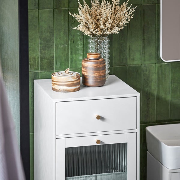 Weißer Badezimmerschrank mit Schublade, Tür mit geriffeltem Glas und dekorativen Gefäßen