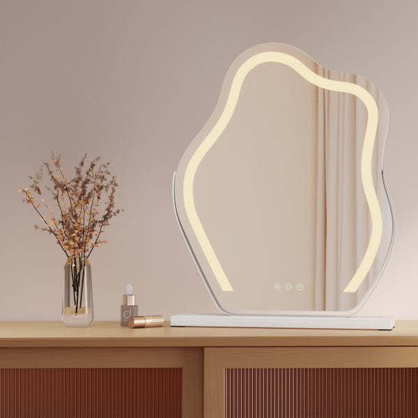 Beleuchteter Kosmetikspiegel mit unregelmäßiger Form auf einem Schminktisch