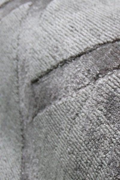 Detailaufnahme eines grauen Teppichs mit strukturierter Oberfläche, Rillenmuster und weichen Textilfasern.