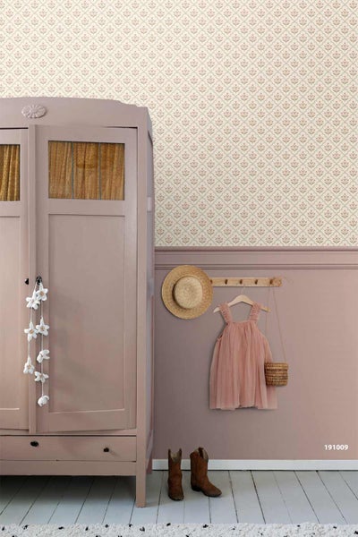 Vliestapete mit floralem Muster über einer Wandleiste in einem Kinderzimmer mit Holzschrank, Kleiderhaken und Holzboden.