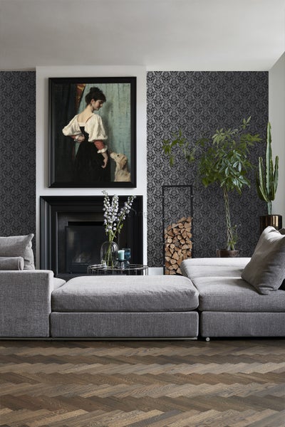 Wohnzimmer mit grauer Couch, Kamin und dekorativer Tapete.