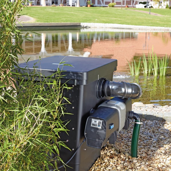 Teichfiltersystem mit UVC-Klärer und elektronischer Steuerung, installiert am Gartenteich neben Bambuspflanzen und Holzhackschnitzeln.