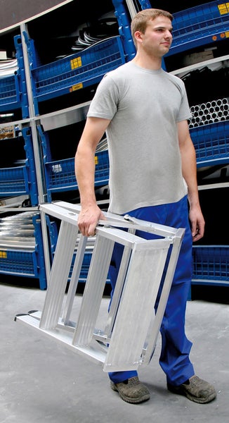 Mann trägt eine zusammengeklappte Aluminiumleiter.