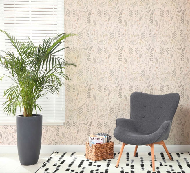 Wohnzimmer mit Vliestapete mit Blumenmuster, einem grauen Sessel und einer großen Zimmerpflanze im Topf vor einem Fenster mit Jalousien.