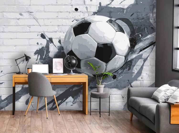 Wohnzimmer mit Fototapete mit Fußballmotiv auf Backsteinwand, Schreibtisch aus Holz, Bürostuhl und Sofa in modernem Design.