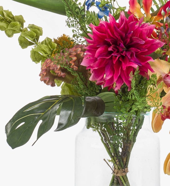 Bunter Blumenstrauß in einer Glasvase mit Strelitzie, Orchideen, Nadelkissen-Protea und Monstera-Blatt.