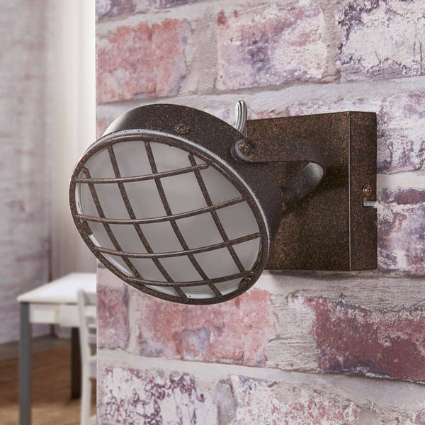 Wandleuchte mit Metallgitter vor einer Ziegelwand