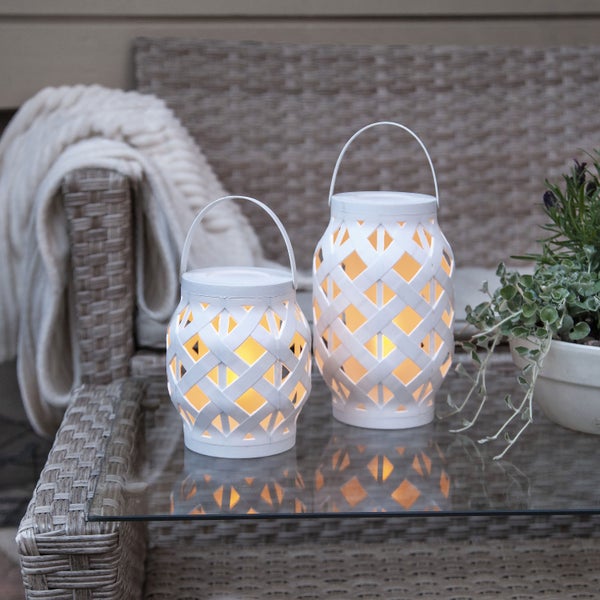 Zwei weiße Laternen mit Tragegriff auf einem Tisch