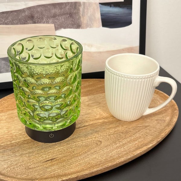 Dekorative Tischleuchte aus Glas neben einer Tasse auf einem Holztablett