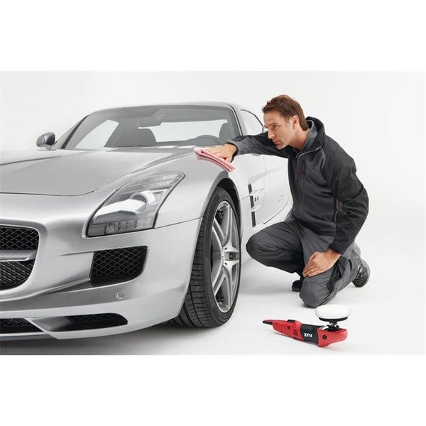 Ein Mann poliert die Motorhaube eines silbernen Sportwagens mit einem Tuch, eine Flex Poliermaschine liegt bereit auf dem Boden.