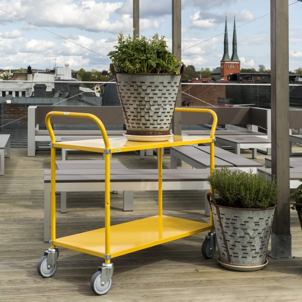 Gelber Servierwagen mit Pflanzen in verzinkten Übertöpfen auf einer Dachterrasse