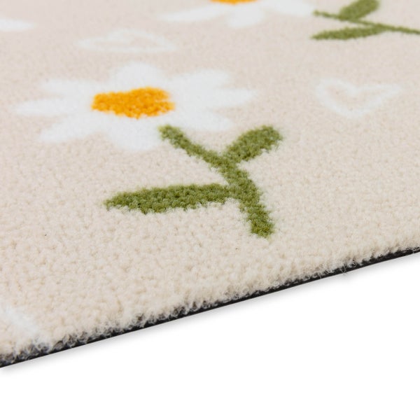 Detailansicht eines flauschigen Teppichs mit Gänseblümchen-Muster und Herzen.