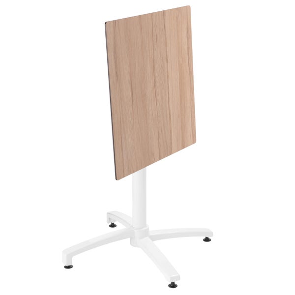 Klappbarer Bistrotisch mit Tischplatte in Eiche-Optik und weißem Metallgestell, Tischplatte senkrecht hochgeklappt.