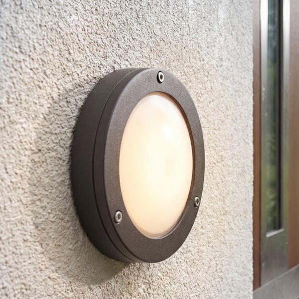 Runde Außenwandleuchte mit warmweißem Licht an einer verputzten Hauswand.