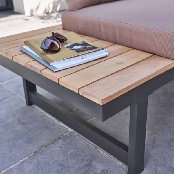 Nahaufnahme eines Gartenlounge-Tisches mit Holzlatten und schwarzem Metallrahmen, auf dem Zeitschriften und eine Sonnenbrille liegen.