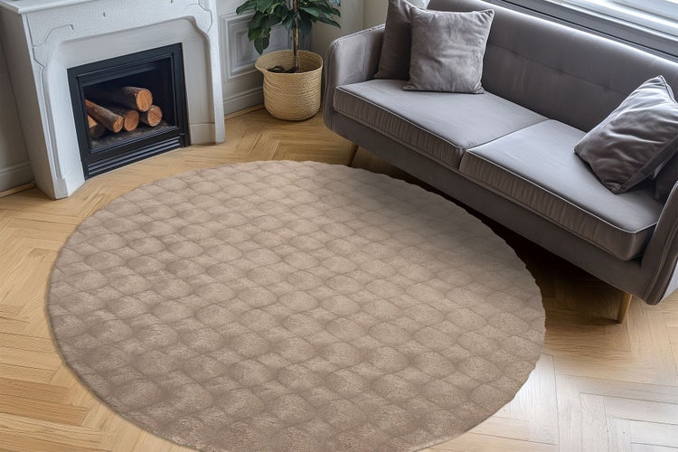 Runder Wohnzimmerteppich mit strukturiertem Muster vor einem Sofa und Kamin auf Parkettboden in einem modern eingerichteten Wohnbereich.