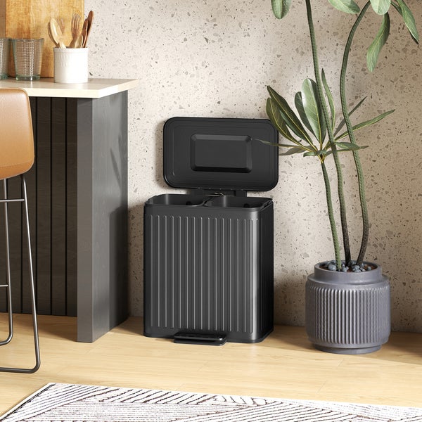 Abfalltrenneimer mit offenem Deckel neben einer Zimmerpflanze