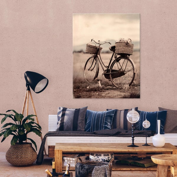 Wandbild mit Motiv eines nostalgischen Fahrrads mit Korb in einem Wohnzimmer mit Couch, Beistelltisch und Pflanze.
