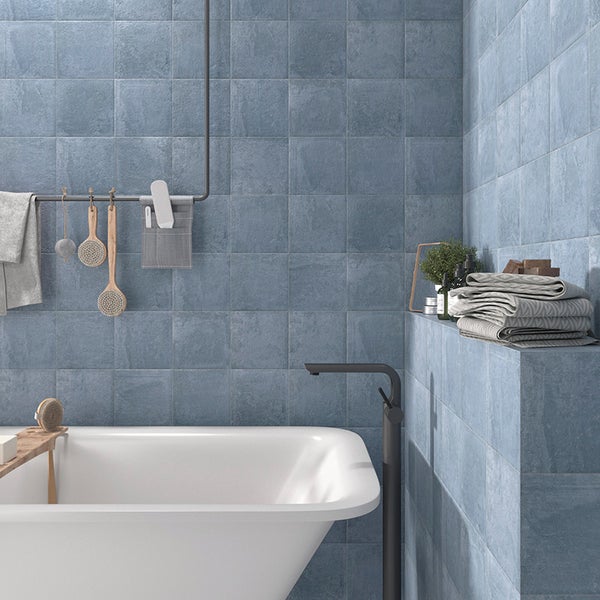 Badezimmer mit quadratischen Wandfliesen, freistehender Badewanne und schwarzen Armaturen in moderner, strukturierter Optik.