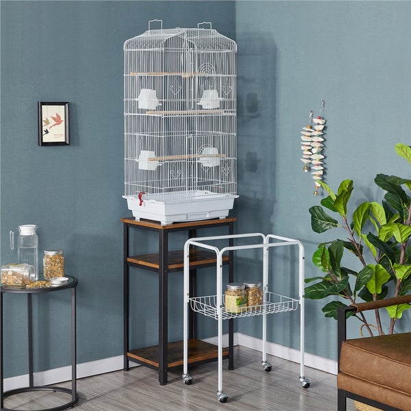 Zimmeransicht mit weißem Vogelkäfig auf einem dunklen Regal mit Holzablagen und einem rollbaren Servierwagen