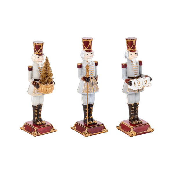 Drei dekorative Nussknacker Figuren als Weihnachtsdekoration auf Sockeln, eine mit beleuchtetem Weihnachtsbaum und eine mit Kalenderwürfeln.