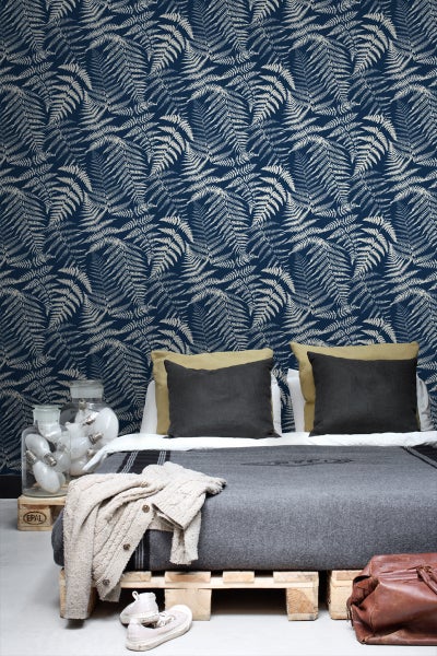 Schlafzimmer mit Farnmuster-Tapete, Bett und dekorativen Elementen