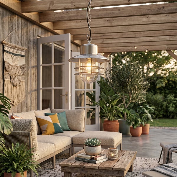 Metall-Außenpendelleuchte über einer hellen Terrasse mit Sofa, Couchtisch aus Holz und einer Holzpergola im Gartenbereich.