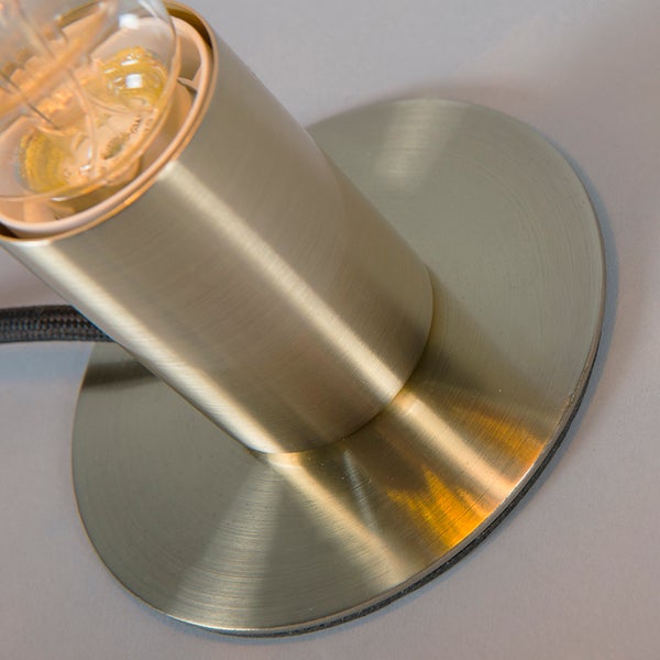 Nahaufnahme von Tischlampenfuß und Fassung aus gebürstetem Metall mit Textilkabel.