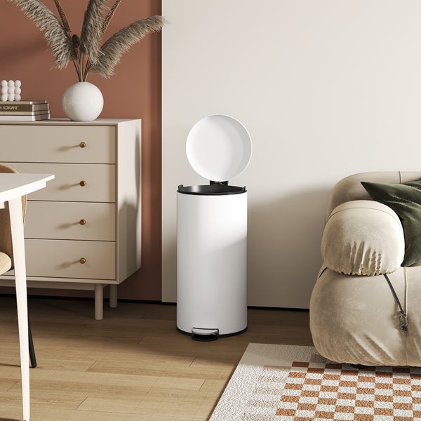 Zimmerszene mit einem runden, weißen Treteimer mit geöffnetem Deckel, einem Sideboard, einem Sofa und einem Teppich