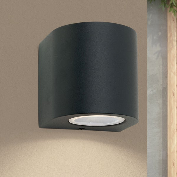 Schwarze Wandaußenleuchte mit abgerundeter Front und integriertem, nach unten gerichtetem LED-Licht.