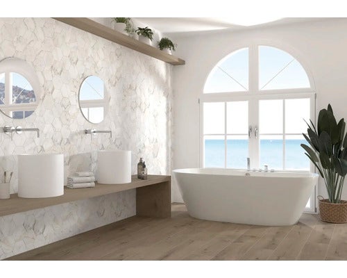 Modernes, helles Badezimmer mit hexagonalen Wandfliesen in Marmoroptik, einer freistehenden Badewanne, zwei Aufsatzbecken und Boden in Holzoptik.