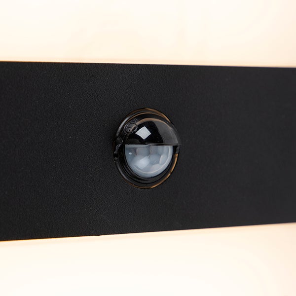 Nahaufnahme eines Bewegungsmelders an einer schwarzen Außenleuchte.