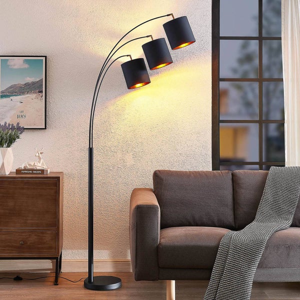 Stehlampe mit drei Leuchten in einem Wohnzimmer mit Sofa und Kommode.