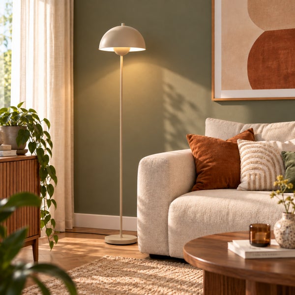Moderne Stehlampe mit kuppelförmigem Schirm neben einem hellen Sofa in einem wohnlich eingerichteten Wohnzimmer mit Zimmerpflanzen und Holztisch