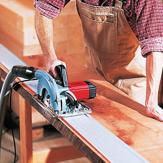 Handwerker beim Zuschneiden eines Holzbretts mit einer Tauchkreissäge auf einer Führungsschiene