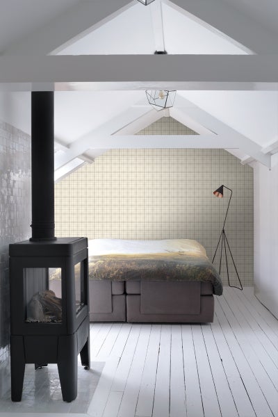 Helles Schlafzimmer im Dachgeschoss mit Kaminofen, Doppelbett und Stehlampe.