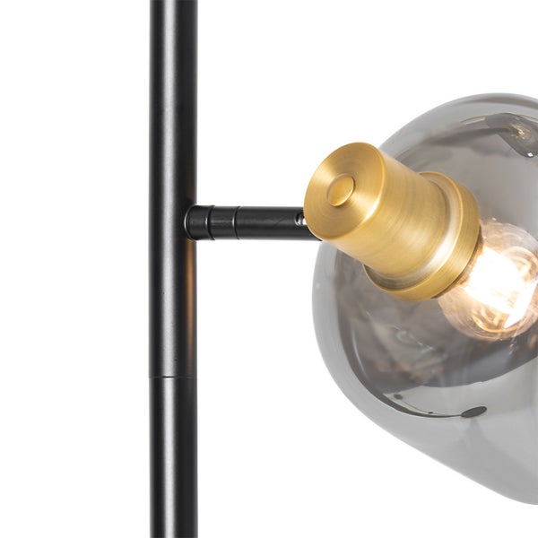 Detailansicht einer Leuchte mit Schirm aus Rauchglas, Fassung in Messingoptik und schwarzem Metallgestell.