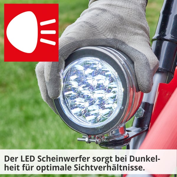 Nahaufnahme eines LED-Scheinwerfers, der von einer Hand mit Schutzhandschuh gehalten wird.