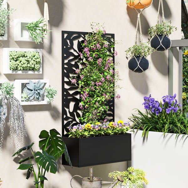 Schwarzer Wandpflanzkasten aus Metall mit Rankgitter und dekorativem Blattmuster, bepflanzt mit Blumen auf einer hellen Balkonwand.