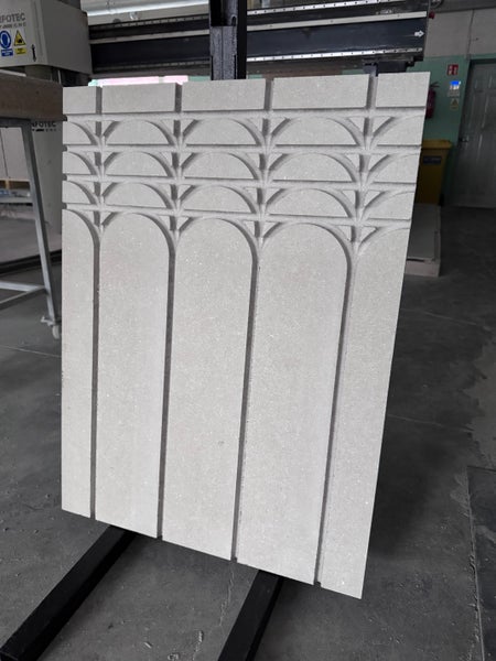 Dekoratives Wandpaneel aus Stein mit eingraviertem Bogenmuster und geometrischem Design.