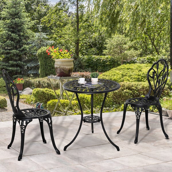 Dreiteiliges Bistroset aus Metall mit floralem Muster, bestehend aus einem runden Tisch und zwei Stühlen auf einer hellen Gartenterrasse.