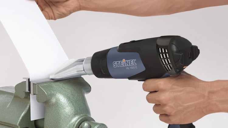 Heißluftgebläse Steinel HL 1920 E beim Erhitzen eines in einen Schraubstock eingespannten Werkstücks.