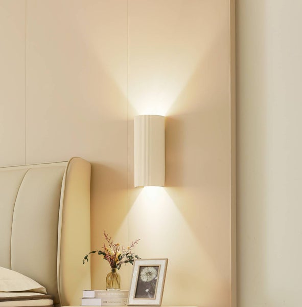 Wandleuchte aus Keramik neben einem Bett