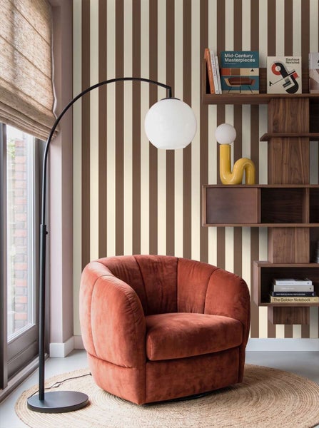 Wohnzimmer mit gestreifter Tapete in einem modernen Einrichtungsstil mit Sessel und Bogenlampe.