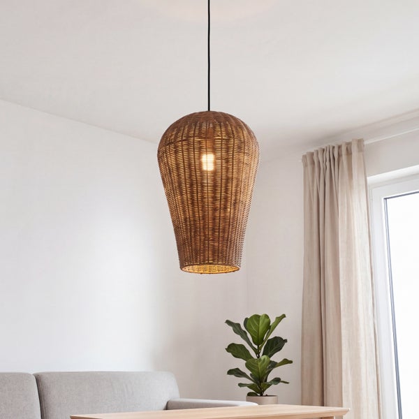 Eine konische Hängelampe aus geflochtenem Rattan hängt über einem Sofa in einem hellen Wohnzimmer.