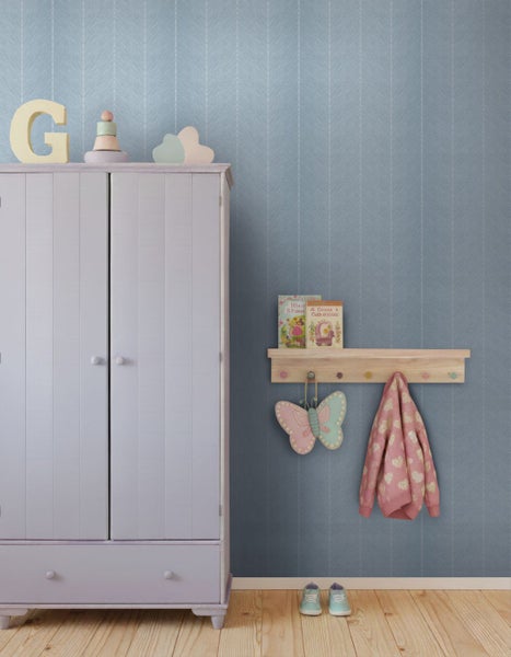 Kinderzimmer mit hellblauer Fischgräten-Tapete, Wandpaneelen, Bambusleiter, Rattansessel mit Kuscheltieren und hellem Teppich.