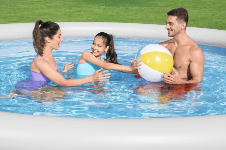 Familie spielt mit Wasserball in einem runden aufblasbaren Pool auf einer Rasenfläche im Garten.